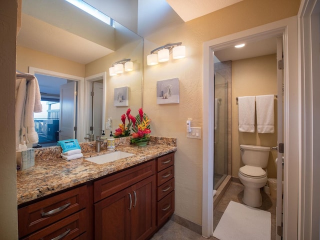 bathroom featuring a shower with door, vanity, and toilet