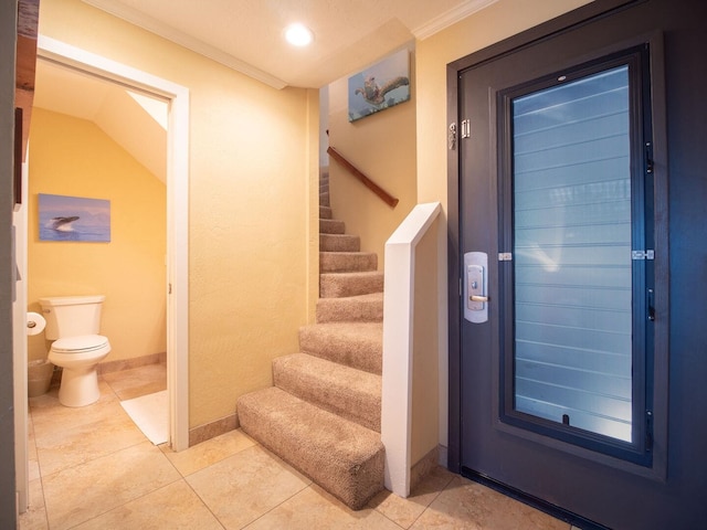 foyer entrance with tile patterned flooring and ornamental molding