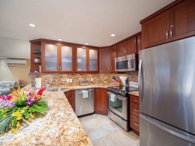 kitchen with sink, light stone counters, a wall mounted AC, light tile patterned flooring, and appliances with stainless steel finishes