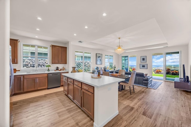 kitchen with appliances with stainless steel finishes, light wood finished floors, open floor plan, light countertops, and a sink