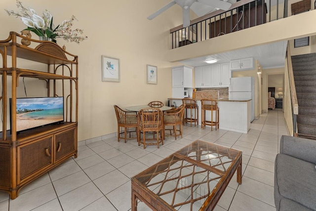 living room with ceiling fan, light tile patterned floors, and a high ceiling