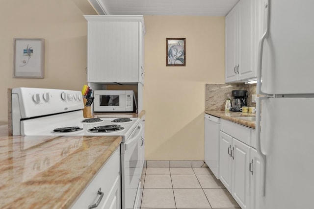 kitchen featuring white appliances, light stone countertops, backsplash, white cabinets, and light tile patterned floors