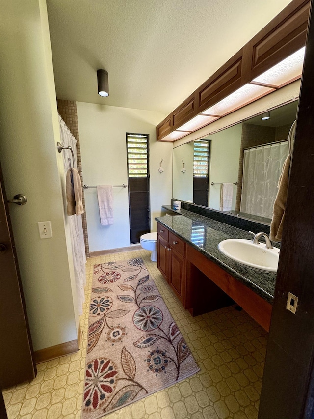 bathroom with walk in shower, vanity, a textured ceiling, and toilet