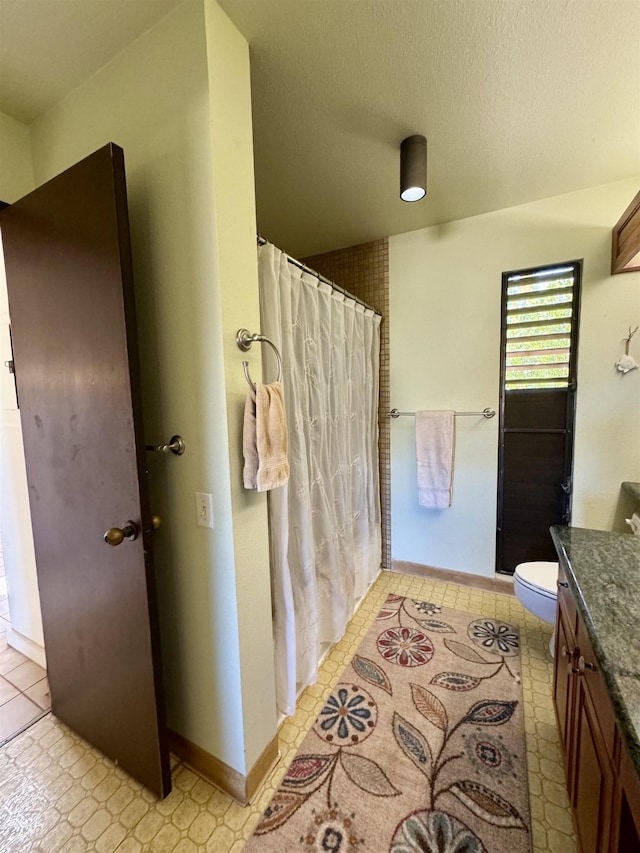 bathroom with tile patterned floors, vanity, a textured ceiling, and toilet