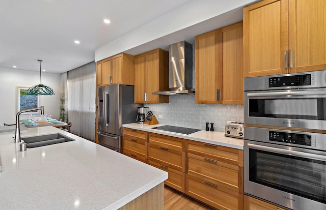 kitchen featuring pendant lighting, sink, appliances with stainless steel finishes, decorative backsplash, and wall chimney exhaust hood