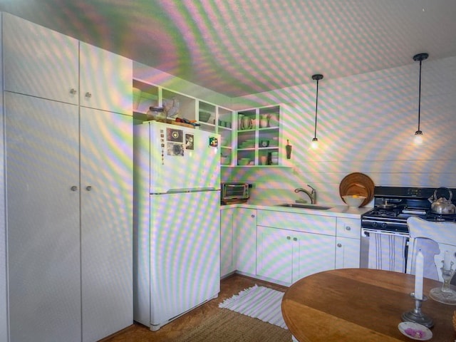 kitchen with black gas range, sink, decorative light fixtures, and white fridge