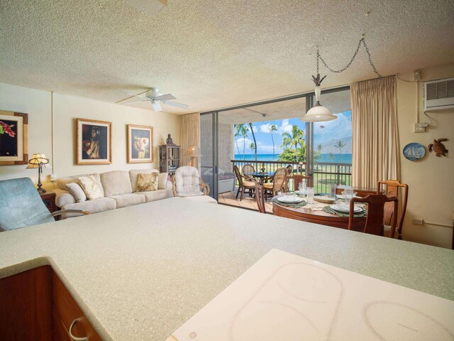 interior space featuring a wall unit AC, ceiling fan, access to exterior, floor to ceiling windows, and a textured ceiling