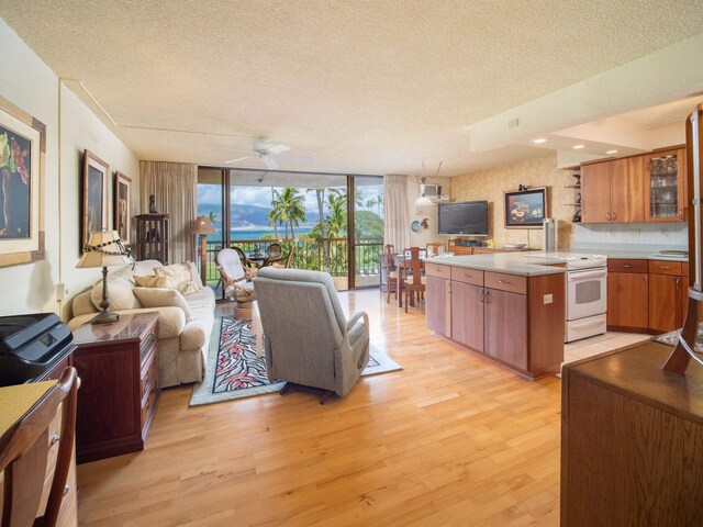 living room featuring a textured ceiling, ceiling fan, expansive windows, and light hardwood / wood-style floors