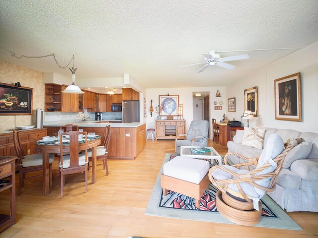 living room with a textured ceiling, light hardwood / wood-style flooring, and ceiling fan