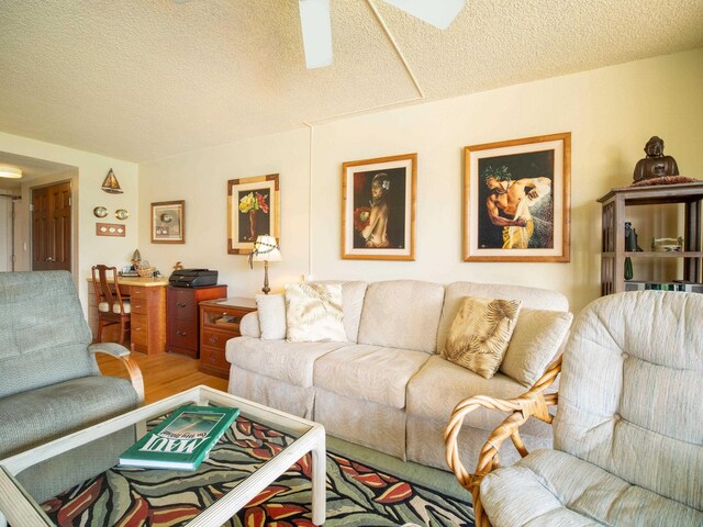 living room with ceiling fan, hardwood / wood-style flooring, and a textured ceiling