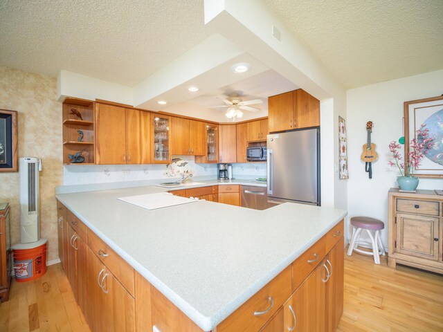 kitchen with appliances with stainless steel finishes, a textured ceiling, ceiling fan, and light hardwood / wood-style floors