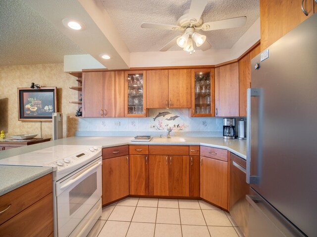 kitchen with appliances with stainless steel finishes, a textured ceiling, sink, and ceiling fan