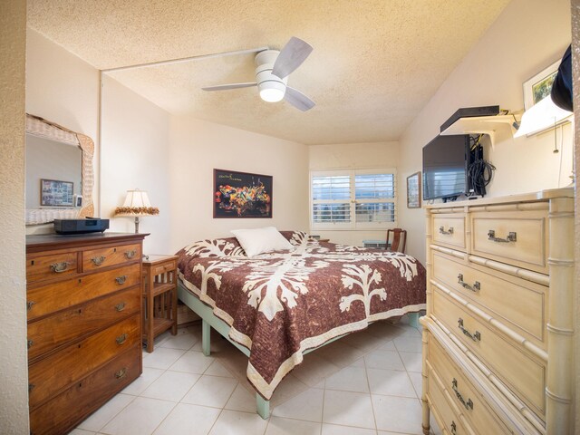 bedroom with a textured ceiling, light tile patterned floors, and ceiling fan