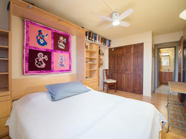 bedroom with a textured ceiling, ceiling fan, a closet, and light hardwood / wood-style floors