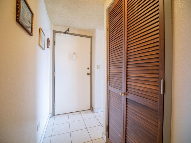 corridor with a textured ceiling and light tile patterned floors