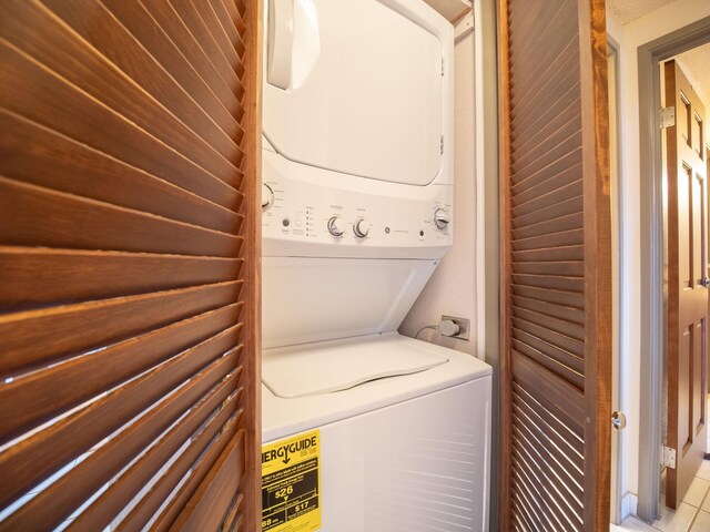 laundry area featuring stacked washer / drying machine and light tile patterned flooring