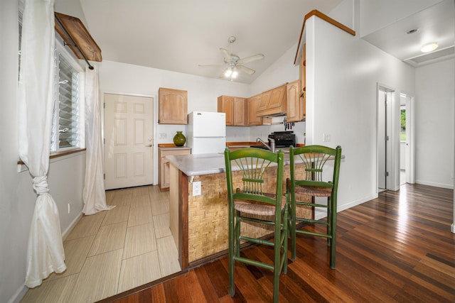 kitchen with a kitchen bar, dark hardwood / wood-style flooring, white fridge, and lofted ceiling