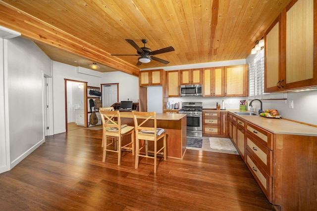 kitchen featuring stainless steel appliances, sink, dark hardwood / wood-style floors, a kitchen island, and a breakfast bar area