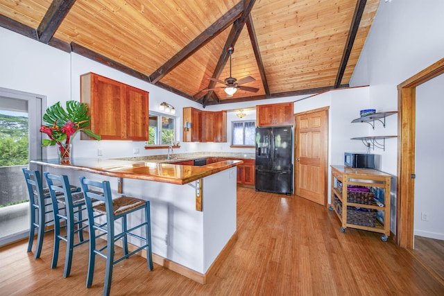 kitchen with black appliances, ceiling fan, light wood-type flooring, beamed ceiling, and kitchen peninsula