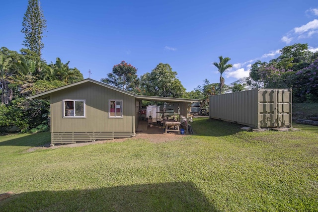 back of house with a storage unit and a lawn