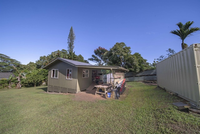 rear view of house featuring an outdoor structure and a lawn