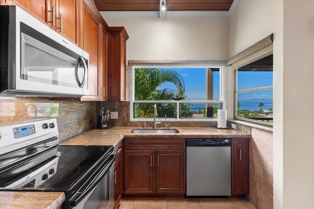 kitchen featuring light tile patterned floors, stainless steel appliances, sink, and backsplash