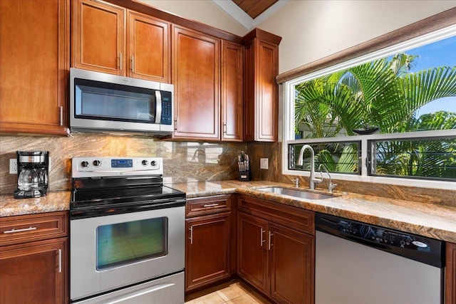 kitchen with lofted ceiling, sink, appliances with stainless steel finishes, and light stone counters