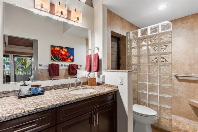 bathroom with vanity, toilet, tile walls, and tiled shower