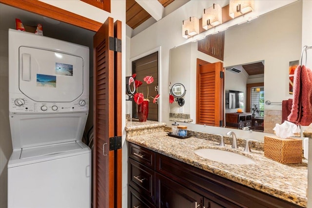 bathroom with vanity, beamed ceiling, and stacked washer and dryer