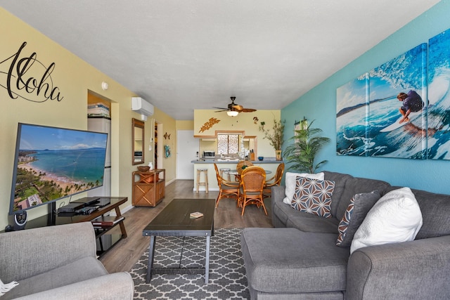 living room with a wall mounted air conditioner, hardwood / wood-style floors, and ceiling fan