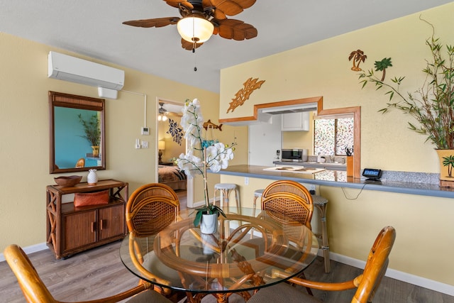 dining room featuring wood-type flooring, ceiling fan, and a wall mounted air conditioner