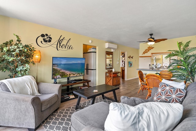 living room with ceiling fan, hardwood / wood-style flooring, and a wall unit AC