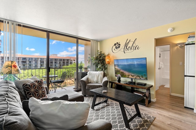 living room featuring floor to ceiling windows, a textured ceiling, a wealth of natural light, and light hardwood / wood-style floors