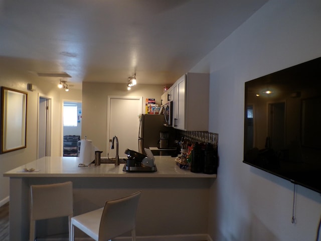 kitchen with kitchen peninsula, tasteful backsplash, a breakfast bar area, and appliances with stainless steel finishes