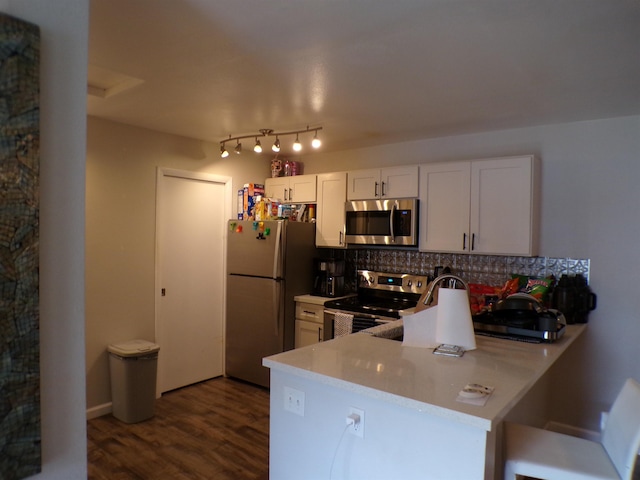 kitchen featuring white cabinets, dark wood-type flooring, stainless steel appliances, tasteful backsplash, and kitchen peninsula