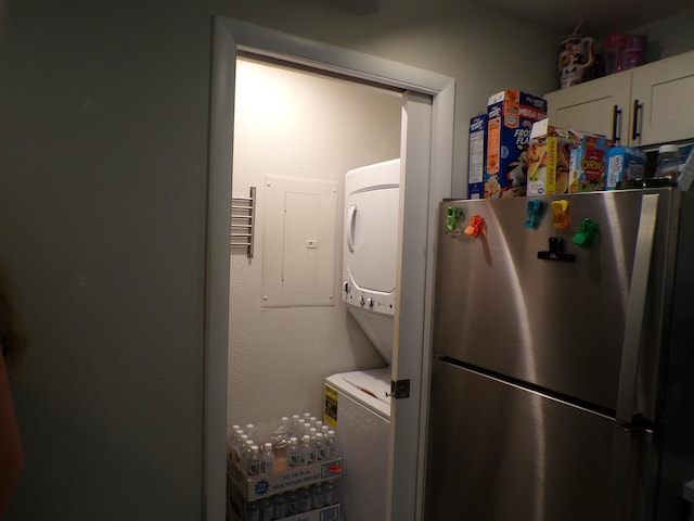 laundry room featuring electric panel and stacked washing maching and dryer