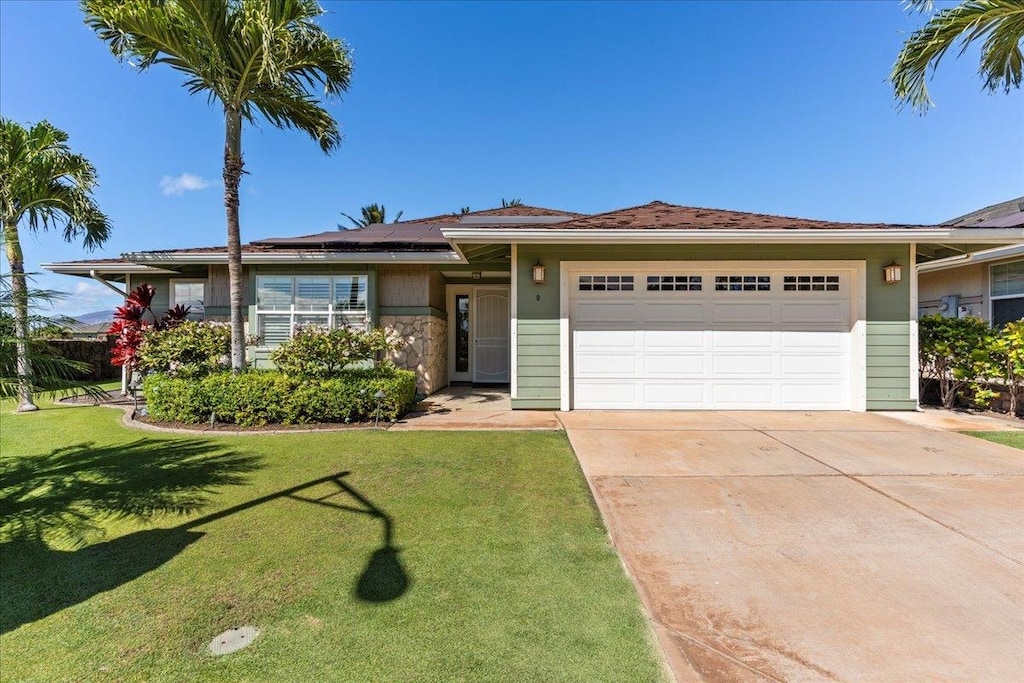 view of front of house with solar panels, a garage, and a front yard