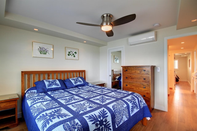 bedroom with ceiling fan, light hardwood / wood-style flooring, and a wall unit AC