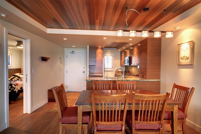 dining room featuring ceiling fan, sink, a raised ceiling, wood ceiling, and dark hardwood / wood-style flooring