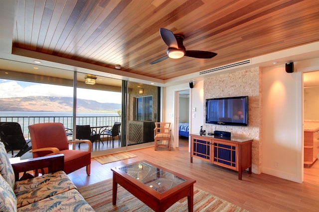 living room with a water and mountain view, light hardwood / wood-style flooring, wood ceiling, and ceiling fan