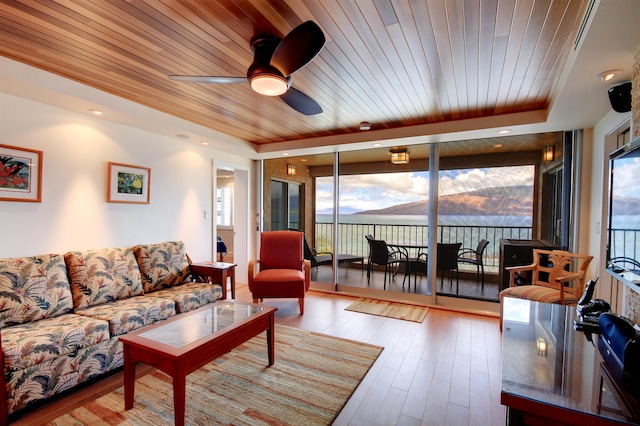 living room with light hardwood / wood-style floors, a tray ceiling, wooden ceiling, and ceiling fan