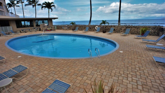 view of pool featuring a patio area and a water view