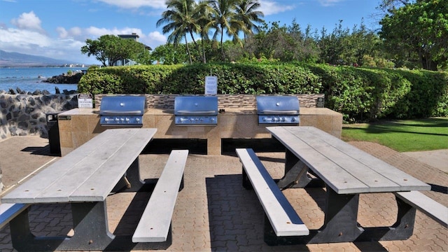 view of patio / terrace featuring exterior kitchen, area for grilling, and a water view