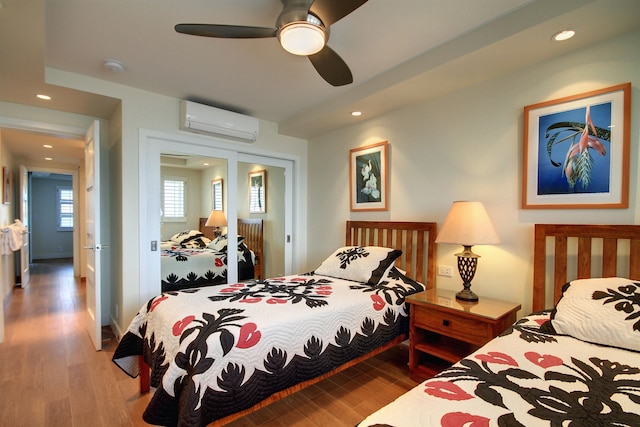 bedroom featuring an AC wall unit, a closet, ceiling fan, and dark hardwood / wood-style flooring