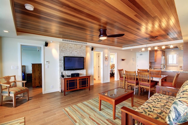 living room with wooden ceiling, light wood-type flooring, and a raised ceiling