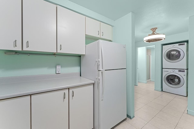 2747 S Kihei Rd Unit D102, Kihei, HI 96753 - kitchen featuring freestanding refrigerator, stacked washing machine and dryer, light tile patterned floors, light countertops, and white cabinets