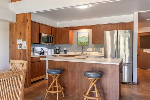 kitchen with a center island, stainless steel appliances, sink, dark tile flooring, and a kitchen bar