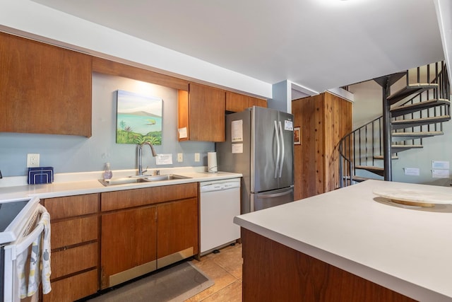 kitchen with stove, stainless steel refrigerator, sink, dishwasher, and light tile floors