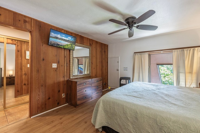 bedroom with tile flooring, wooden walls, and ceiling fan