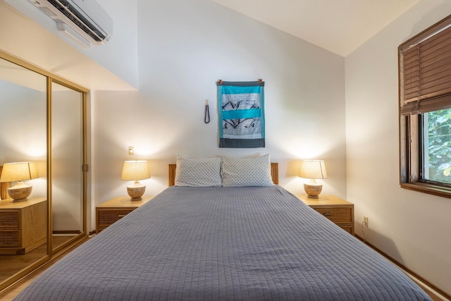 bedroom with an AC wall unit, a closet, vaulted ceiling, and hardwood / wood-style flooring